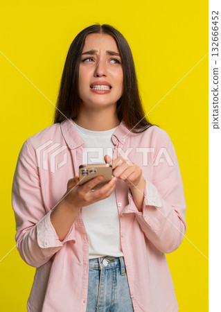 Woman panicking tapping smartphone screen reacting in fear after deleting something by mistake Woman panicking tapping smartphone screen reacting in fear after deleting something by mistake 132666452