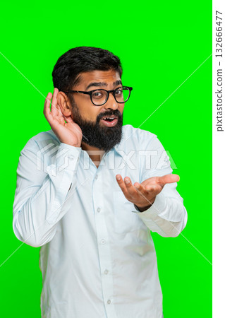 Indian man frowning and holding hand to ear pretending not to hear showing confusion, surprise Indian man frowning and holding hand to ear pretending not to hear showing confusion, surprise 132666477