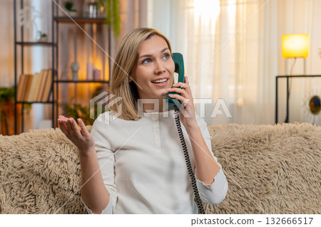 Woman talking on vintage phone at home, emotionally gesturing with hand during intense conversation 132666517