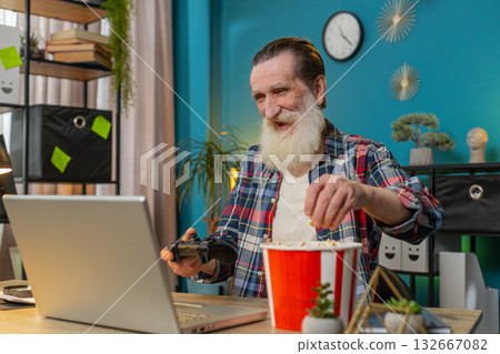 Excited happy senior man celebrating victory in play video game on laptop using controller joystick Excited happy senior man celebrating victory in play video game on laptop using controller joystick 132667082