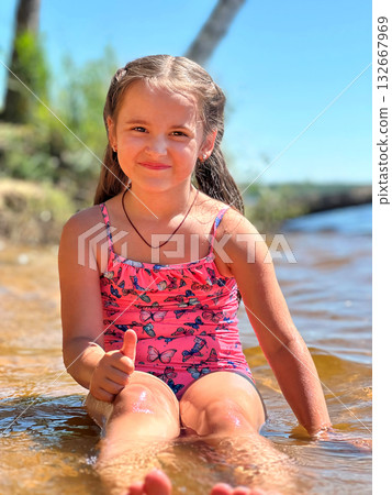 A Joyful Girl Having Fun While Playing in Water on a Bright Sunny Day 132667969