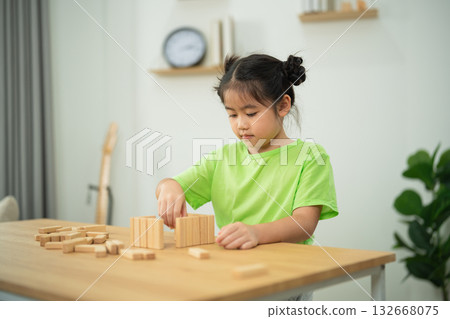 Child Playing with Wooden Blocks in a Bright Room, Engaging in Creative Playtime Activity, Focused on Building and Learning Skills Child Playing with Wooden Blocks in a Bright Room, Engaging in Creative Playtime Activity, Focused on Building and Learning Skills 132668075