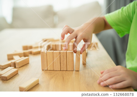 Child's hand building structure with wooden blocks on table, creativity and play, educational activity at home, early childhood development and learning experience 132668078