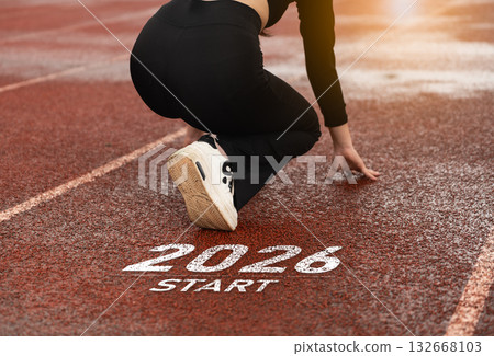 Athletic athlete prepares to sprint from starting line marked 2026 on outdoor track, demonstrating focus and determination in a competitive environment, Happy new year concept. 132668103