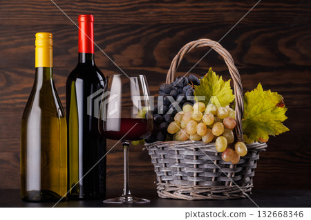 Red and white wine bottles with a glass and basket of fresh grapes Red and white wine bottles with a glass and basket of fresh grapes 132668346