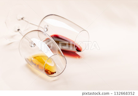 Wine glasses with red and white wine lying on beige background Wine glasses with red and white wine lying on beige background 132668352