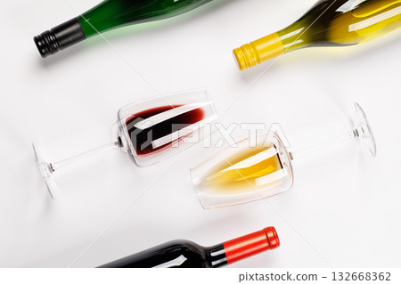 Wine glasses with red and white wine and bottles lying on white background 132668362