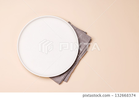 Empty plate and towel on beige table top view Empty plate and towel on beige table top view 132668374