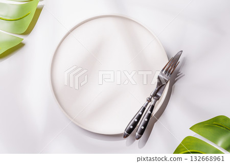 Empty plate on white background with leaves and shadows, food mockup with natural light Empty plate on white background with leaves and shadows, food mockup with natural light 132668961