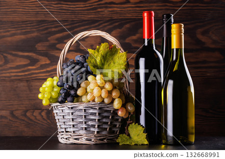 Red and white wine bottles with a glass and basket of fresh grapes Red and white wine bottles with a glass and basket of fresh grapes 132668991