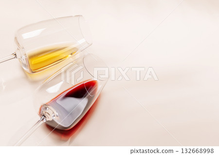 Wine glasses with red and white wine lying on beige background Wine glasses with red and white wine lying on beige background 132668998