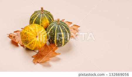 Autumn still life with pumpkins and leaves on beige background 132669056