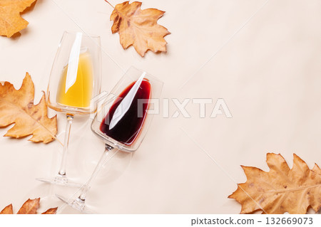 Wine glasses with autumn leaves on beige background Wine glasses with autumn leaves on beige background 132669073