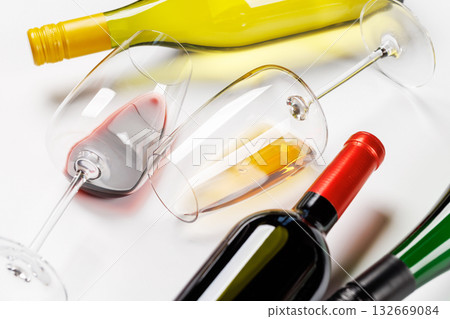 Wine glasses with red and white wine and bottles lying on white background 132669084