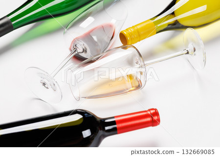 Wine glasses with red and white wine and bottles lying on white background 132669085