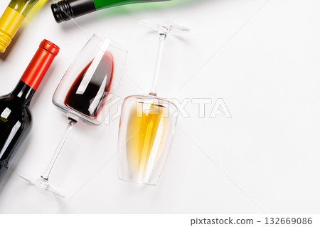 Wine glasses with red and white wine and bottles lying on white background 132669086