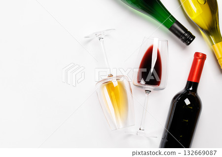 Wine glasses with red and white wine and bottles lying on white background 132669087