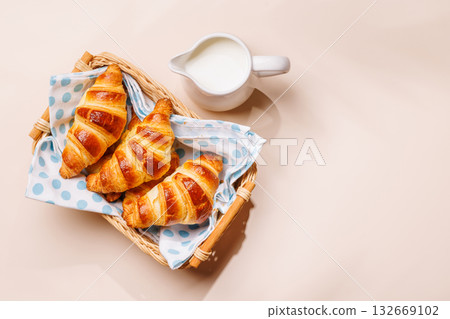 Aromatic croissants in wicker basket with milk jug 132669102