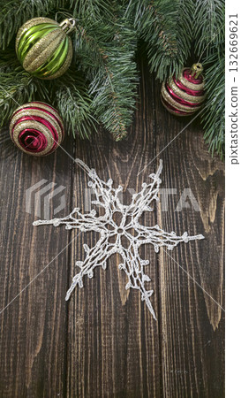A white crocheted snowflake-shaped doily with fir branches and decorations. A white crocheted snowflake-shaped doily with fir branches and decorations. 132669621