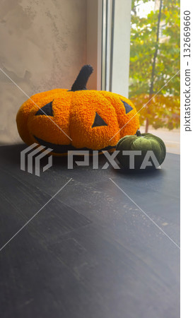 Pumpkin-shaped stuffed animals on a coffee shop windowsill. Holiday decor. Pumpkin-shaped stuffed animals on a coffee shop windowsill. Holiday decor. 132669660
