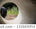 View Through Concrete Drainage Pipe to Green Vegetation and Nature View Through Concrete Drainage Pipe to Green Vegetation and Nature 132669954