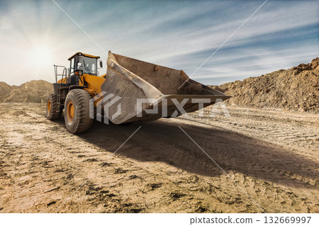 A large yellow bulldozer prepares to move earth at a construction site, illuminated by the warm light of a rising sun, symbolizing early labor A large yellow bulldozer prepares to move earth at a construction site, illuminated by the warm light of a rising sun, symbolizing early labor 132669997