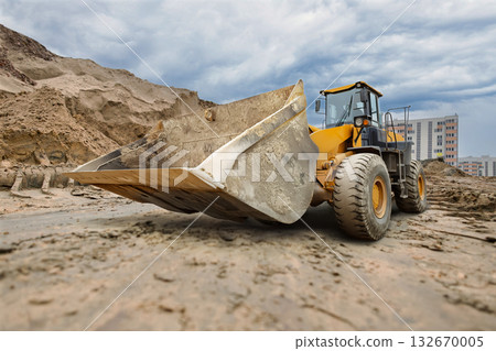 Heavy machinery moves earth and prepares the construction site as dark clouds loom overhead, signaling a change in the weather for the busy workers below Heavy machinery moves earth and prepares the construction site as dark clouds loom overhead, signaling a change in the weather for the busy workers below 132670005