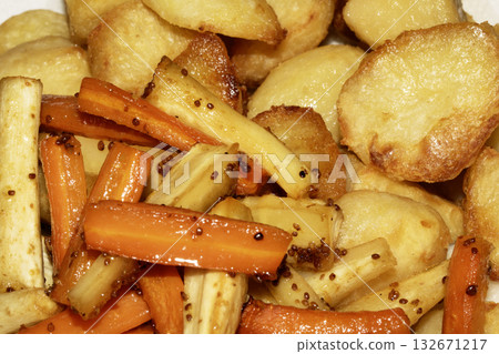 Close up of roasted vegetables crsipy potatoes parsnip and carrots side dish for Sunday roast dinner Close up of roasted vegetables crsipy potatoes parsnip and carrots side dish for Sunday roast dinner 132671217