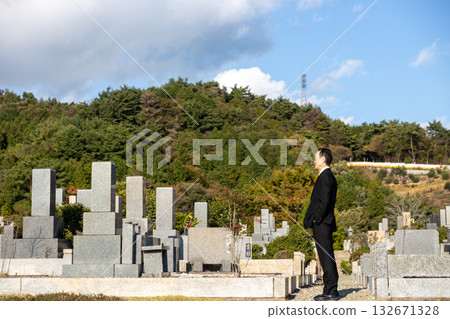 一位身穿喪服的中年男子站在墓園裡。 一位身穿喪服的中年男子站在墓園裡。 132671328