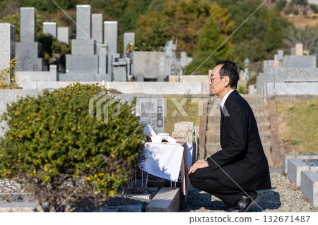 A middle-aged man wearing mourning clothes at the grave for burial A middle-aged man wearing mourning clothes at the grave for burial 132671487