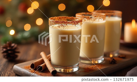 Three glasses of eggnog with cinnamon on a wooden board, surrounded by spices and blurred holiday lights in the background. Cozy holiday concept 132671975