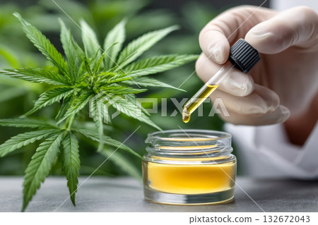 Hand dropping cbd oil into a jar 132672043