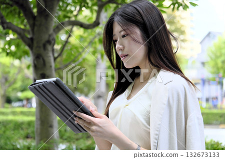 A young businesswoman using a tablet in the greenery of the park A young businesswoman using a tablet in the greenery of the park 132673133