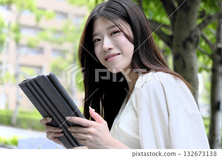 A young businesswoman using a tablet in the greenery of the park A young businesswoman using a tablet in the greenery of the park 132673138