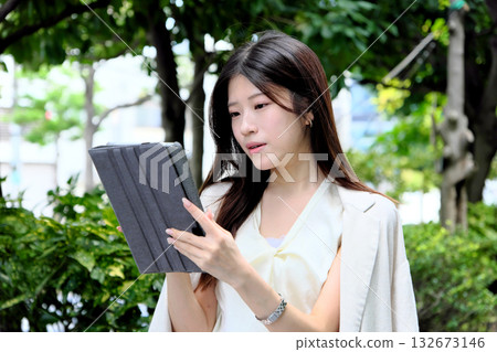 A young businesswoman using a tablet in the greenery of the park A young businesswoman using a tablet in the greenery of the park 132673146
