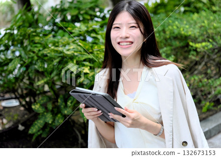A young businesswoman using a tablet in the greenery of the park A young businesswoman using a tablet in the greenery of the park 132673153