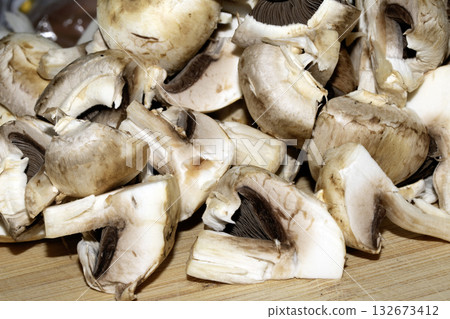 Close up of chopped sliced raw mushrooms on a chopping board prepared for cooking Close up of chopped sliced raw mushrooms on a chopping board prepared for cooking 132673412