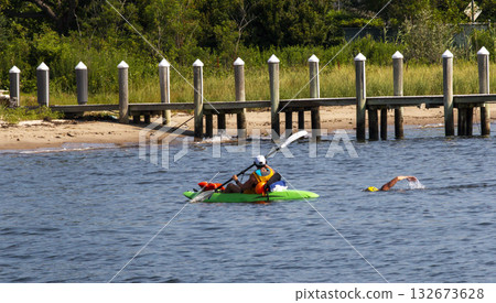 Kayakers Escorting A Swimmer To Shore 132673628