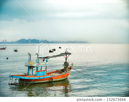 Traditional Thai Fishing Boat Moored in the Sea with Coastal City Skyline in the Distant Foggy Background 132673666