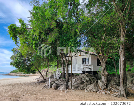 Secluded White Beach Hut or Wooden Cabin on Sand and Rocks, Surrounded by Lush Green Trees on a Tropical Island 132673672