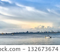 Scenic View of Boats on the Ocean Against a Coastal City Skyline and Soft Evening Sky 132673674