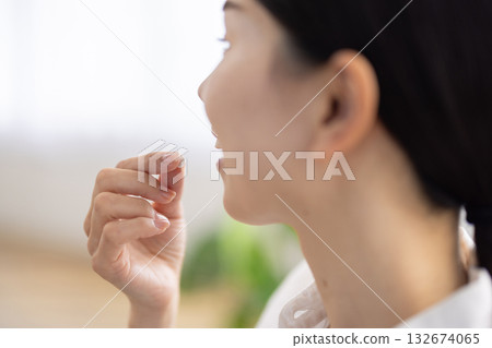 Close-up of a woman's hand holding a pill to her mouth Close-up of a woman's hand holding a pill to her mouth 132674065