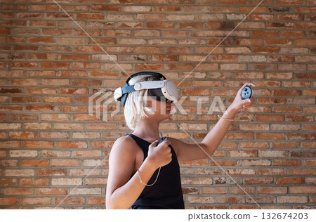 Boy with virtual reality headset playing, holding controllers. Teenager exploring VR game or educational simulation. 132674203