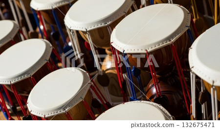 Traditional Korean janggu hourglass drums with white leather heads and colorful red blue rope tensioning system arranged in musical ensemble formation 132675471