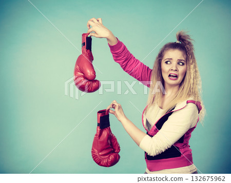 Disgusted woman holding boxing glove Disgusted woman holding boxing glove 132675962