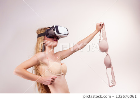 Girl in virtual reality goggles holds bra 132676061