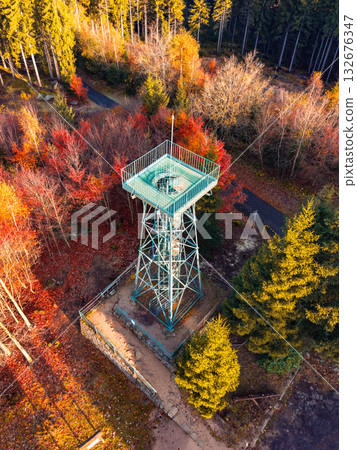 Slovanka Lookout Tower, the oldest iron tower in the Czech Republic, stands tall amidst vibrant autumn foliage in the Jizera Mountains, inviting visitors to enjoy stunning views. 132676347