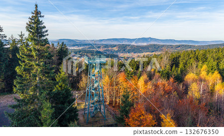 Slovanka Lookout Tower rises above the vibrant autumn foliage of Jizera Mountains. This historic iron tower offers stunning views of the surrounding landscape, showcasing fall colors. Slovanka Lookout Tower rises above the vibrant autumn foliage of Jizera Mountains. This historic iron tower offers stunning views of the surrounding landscape, showcasing fall colors. 132676350