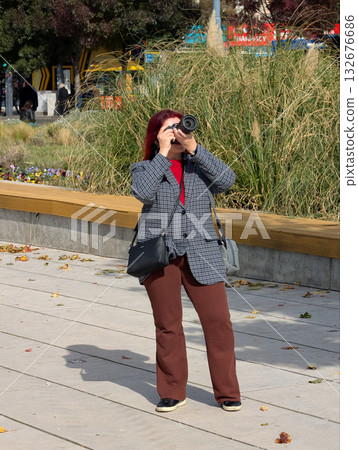 Woman taking photos outdoors with camera. Creative expression, photography lifestyle and artistic observation in urban environment. Woman taking photos outdoors with camera. Creative expression, photography lifestyle and artistic observation in urban environment. 132676686