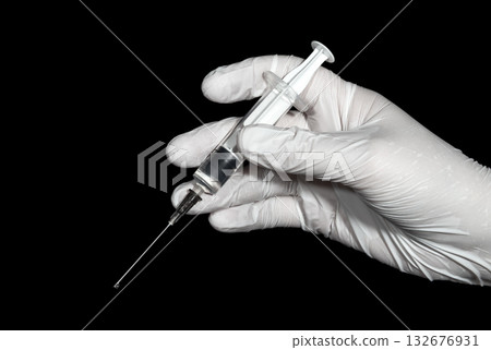 A hand in a white latex glove holds a syringe A hand in a white latex glove holds a syringe 132676931